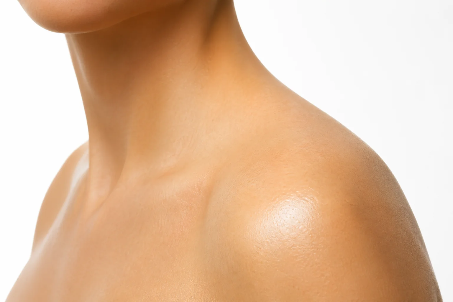 Close-up editorial photograph of healthy luminous skin with a warm golden tone, smooth texture and subtle natural radiance, soft diffused studio lighting, no products visible