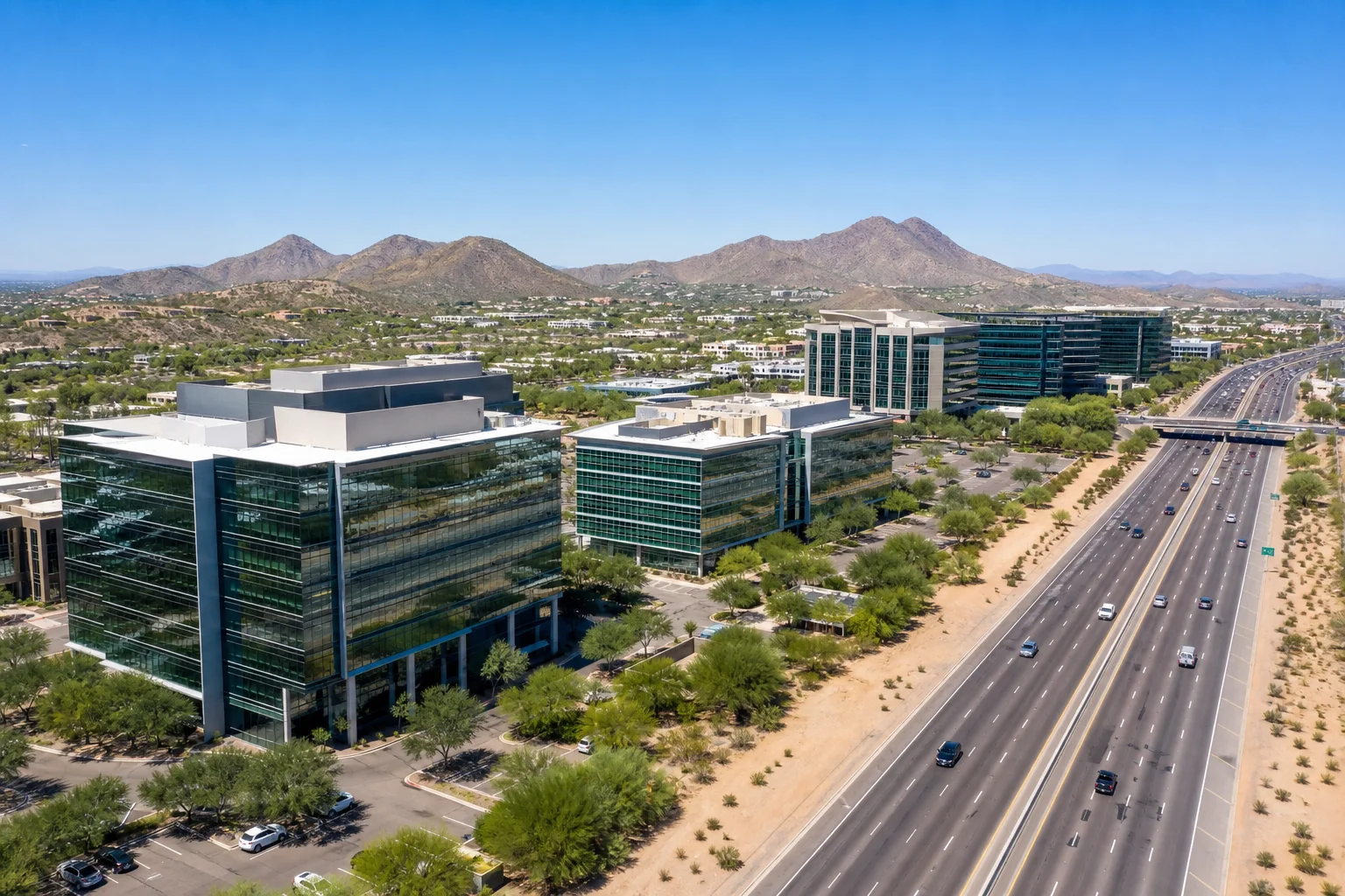 Scottsdale commercial office corridor with glass-facade buildings along the 101 Freeway, desert landscape in the foreground